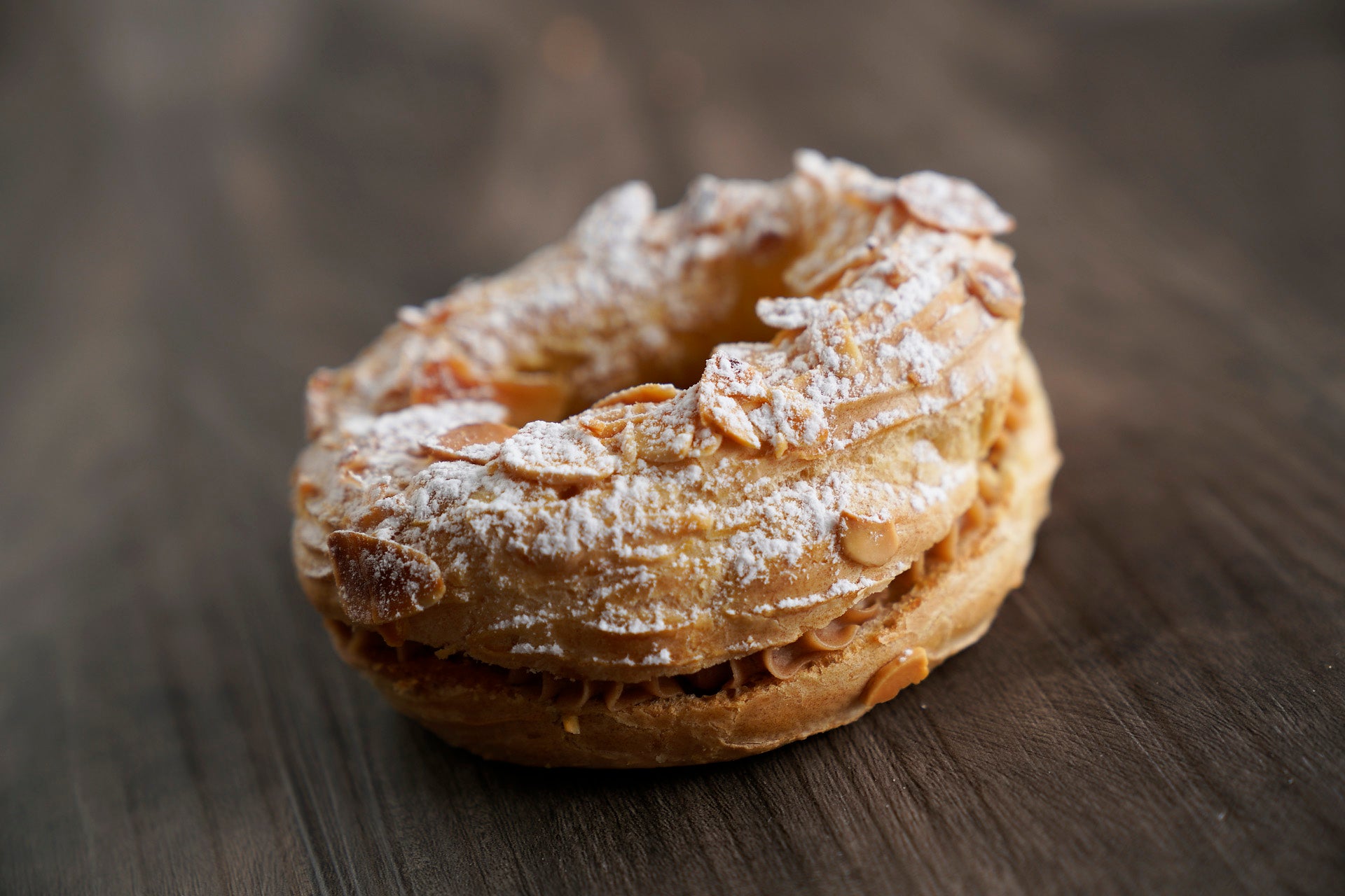 Round choux in the form of a wheel topped with almond slices, filled with hazelnut mousseline and crushed caramelized hazelnuts.